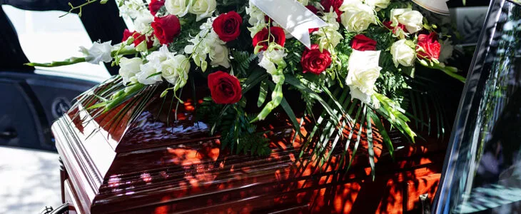 close-up of a casket adorned with a large floral arrangement, often seen during a funeral or graveside service.
