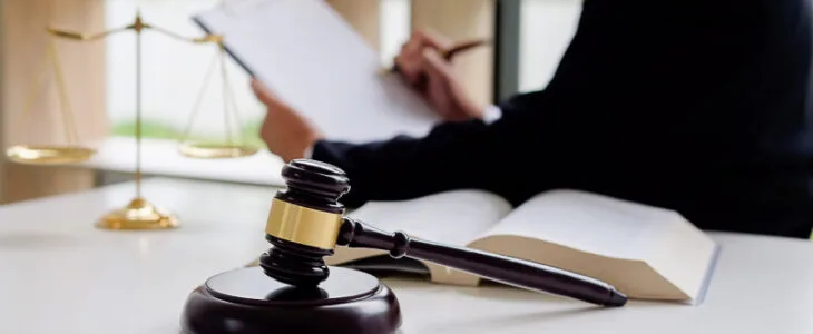Lawyer writing on clipboard with gavel and scales of justice.