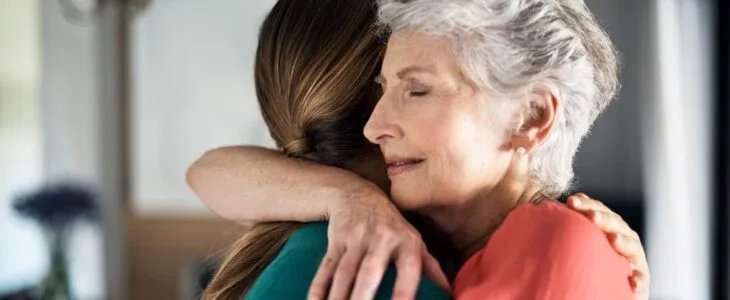 Grandmother and granddaughter hugging emotionally.