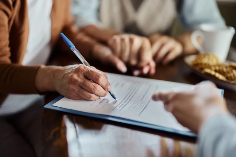 Close up of unrecognizable woman signing a contract during a meeting with insurance agent. Copy space.